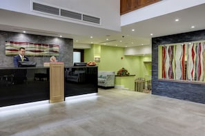 A reception area with a desk, a receptionist, a seating area with a sofa and chairs, and decorative wall art.