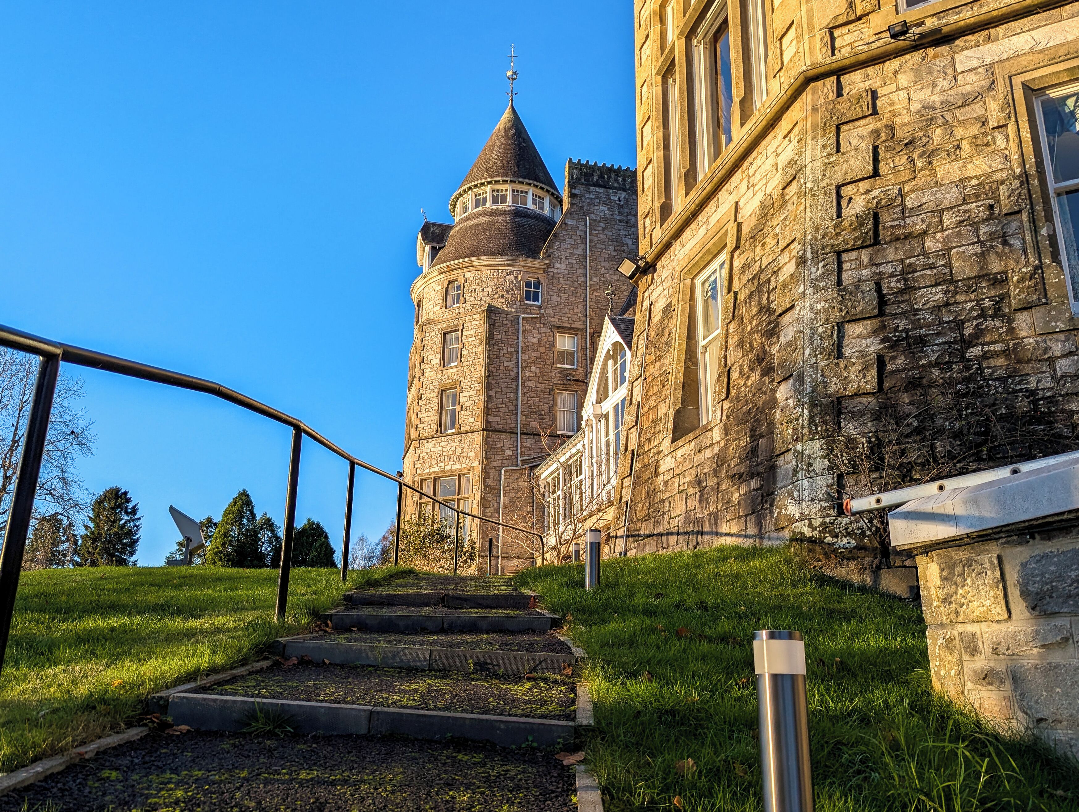 A stone building with a tower, a staircase leading up to it, and a clear blue sky.