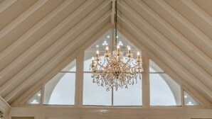 A dining room with a large window, a chandelier, and a red carpet.