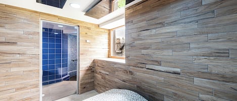 A modern bathroom with wooden wall panels, a shower area, and a bench.
