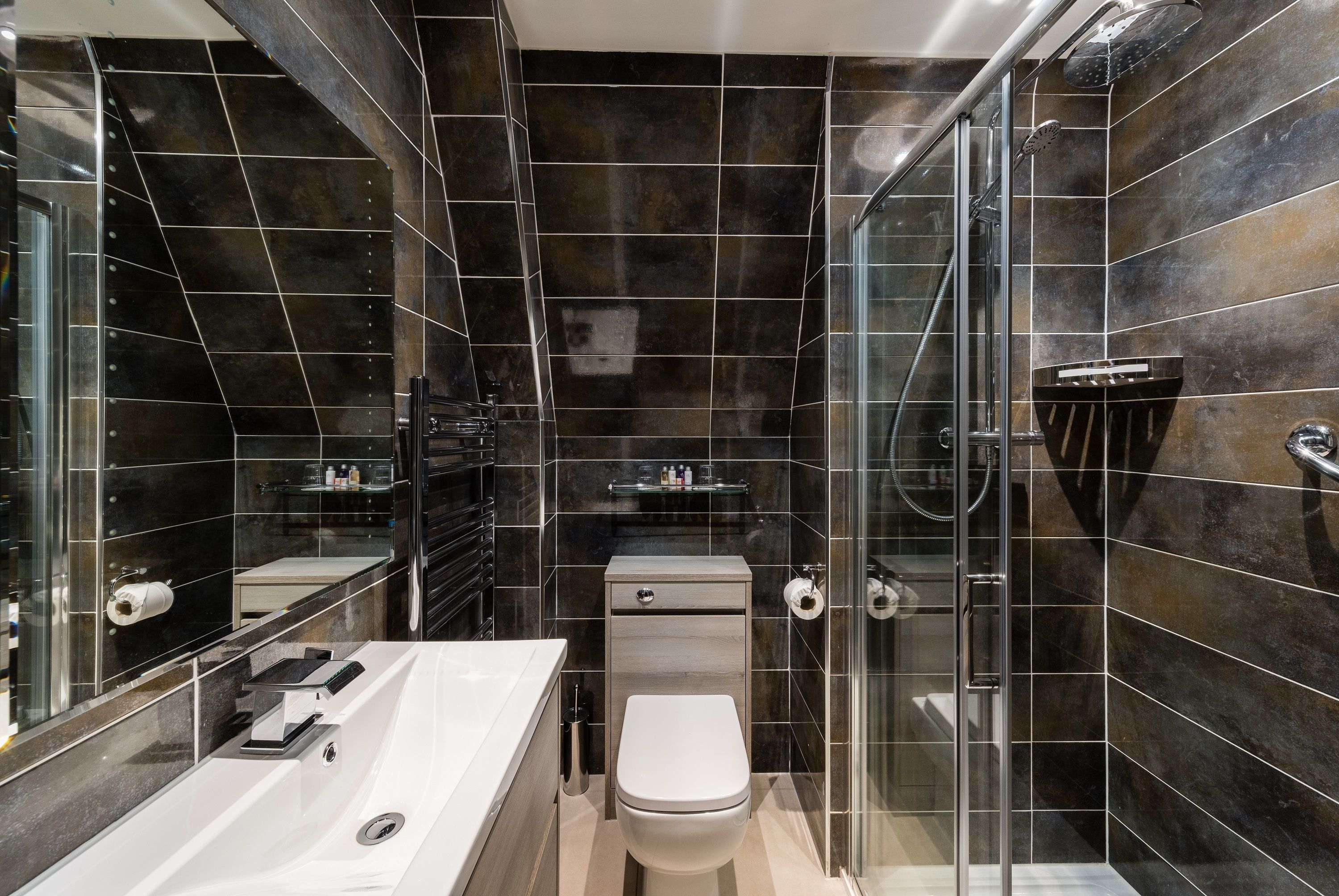 A modern bathroom with a glass-enclosed shower, a white sink, and a toilet.