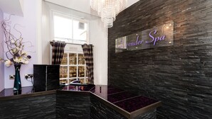 A spa reception area with a black stone wall, a chandelier, and a sign reading "Lavenor Spa".