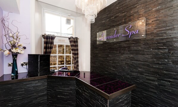 A spa reception area with a black stone wall, a chandelier, and a sign reading "Lavenor Spa". - Atholl Palace Hotel (Pitlochry)
