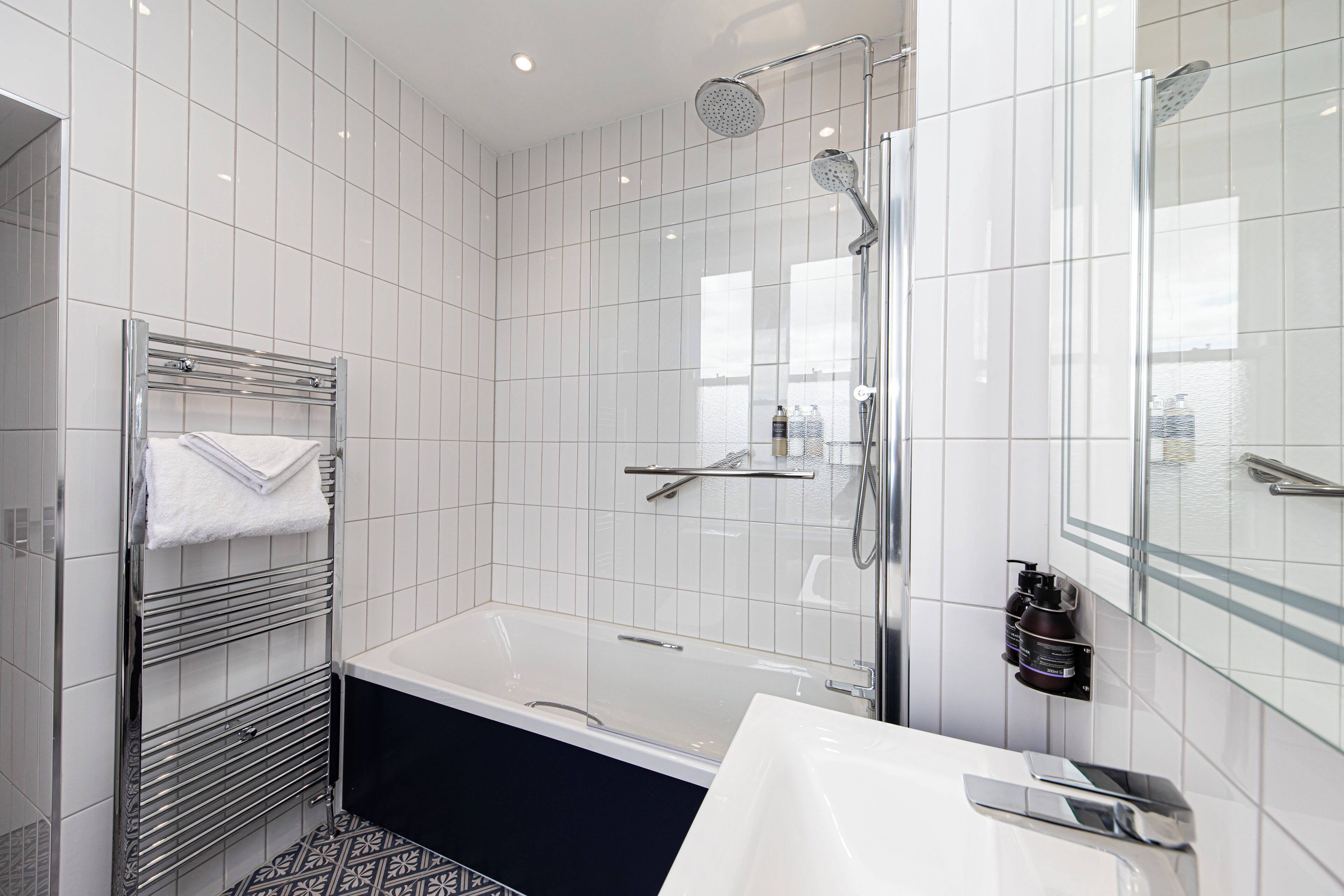 A modern bathroom with a bathtub, a glass-enclosed shower, and a vanity with a mirror.
