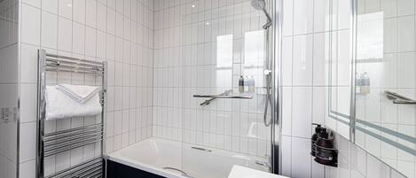 A modern bathroom with a bathtub, a glass-enclosed shower, and a vanity with a mirror.