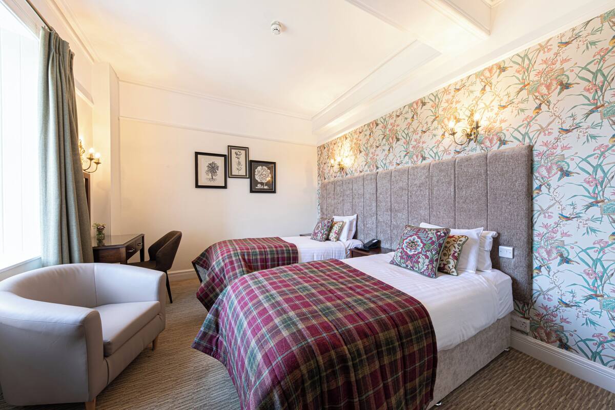Une chambre d’hôtel avec deux lits, un canapé, un bureau et une chaise.