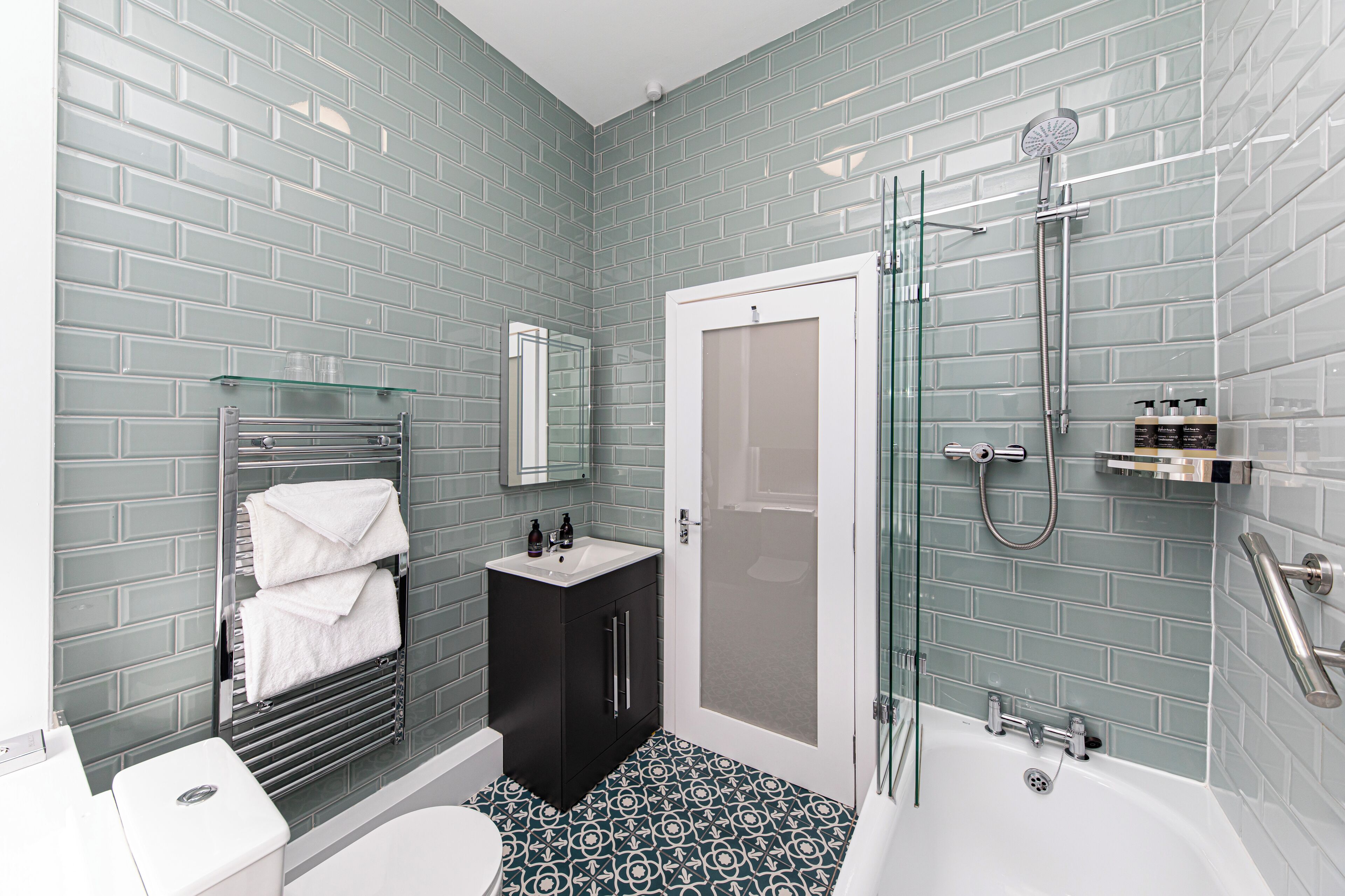 A bathroom with a modern design, featuring a glass shower enclosure, a white sink, and a black vanity.