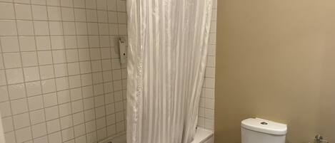Un baño con bañera, inodoro y cortina de ducha.