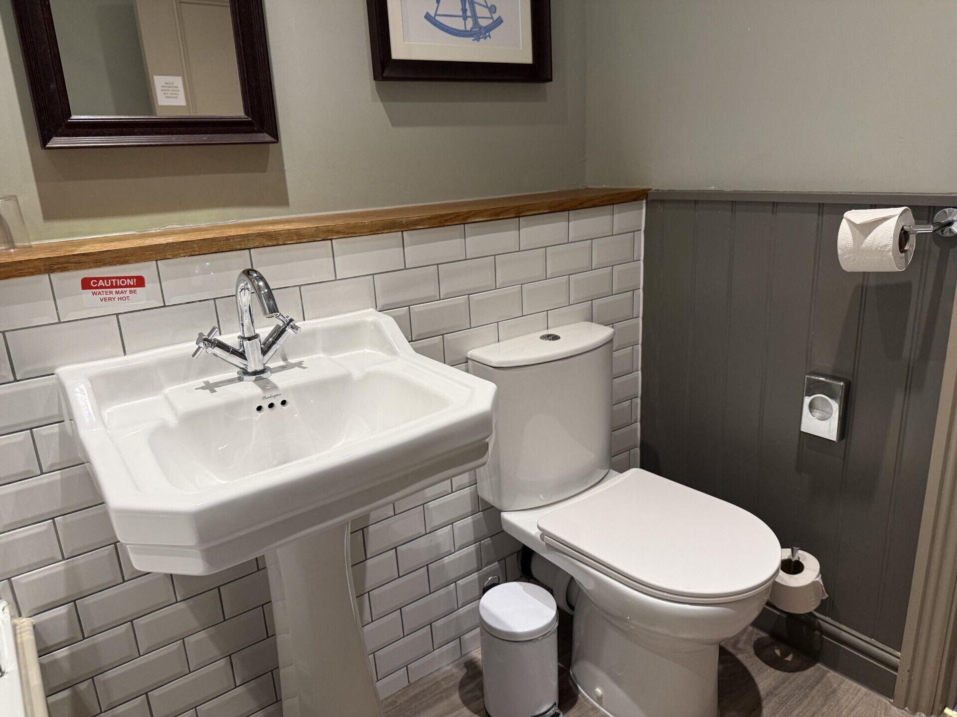 A bathroom with a white sink, a toilet, and a trash can.