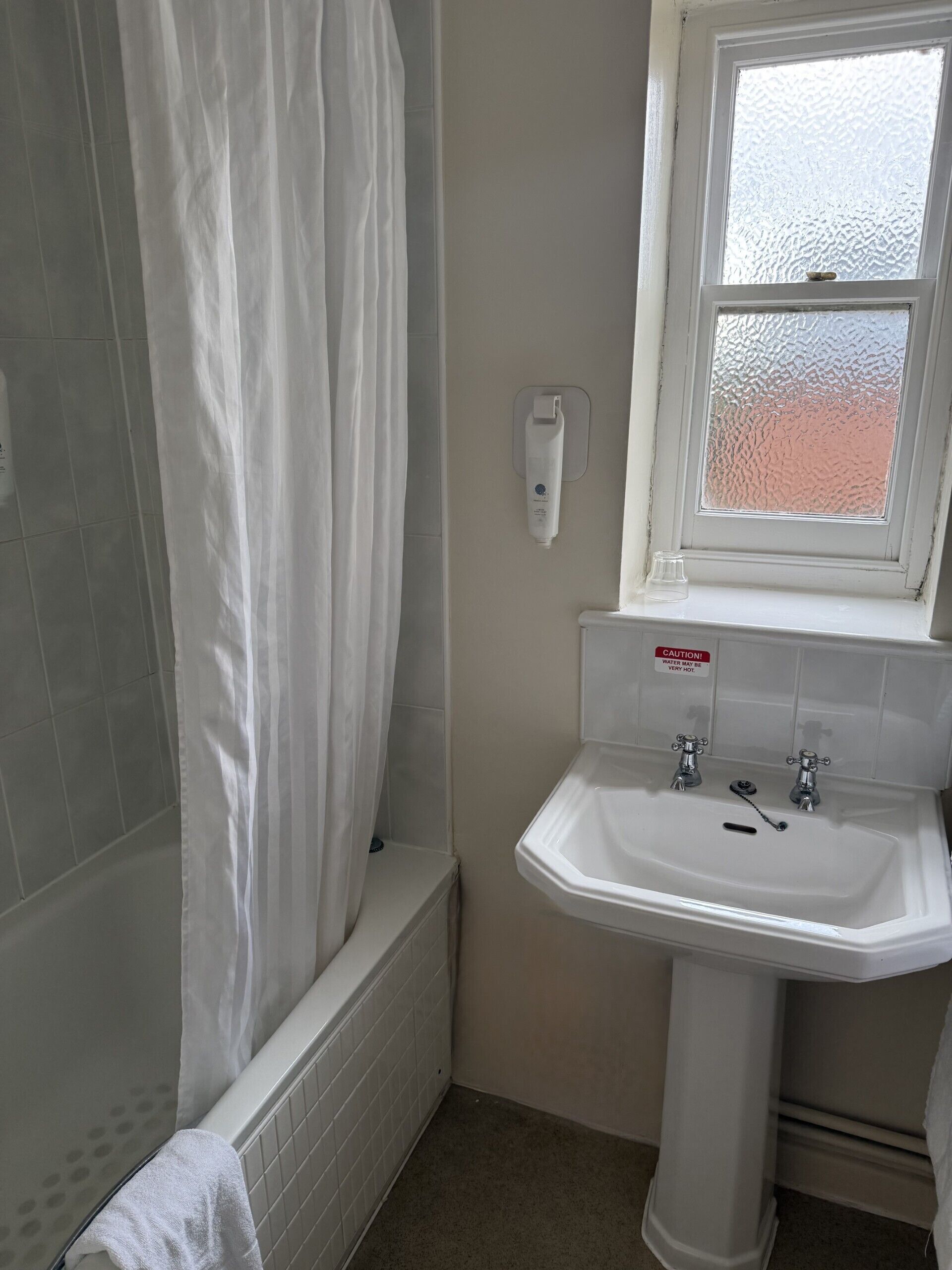 A bathroom with a shower, a sink, and a window.