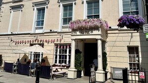 Ein Gebäude mit mehreren Fenstern, einem Schild für 'The Grove Garden Hotel' und einem Schild mit der Aufschrift 'Free Beer'.