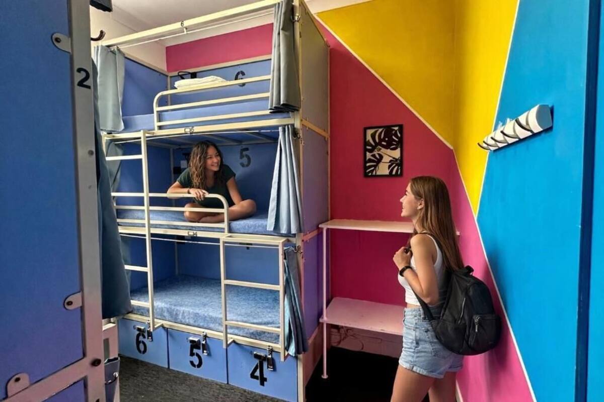 A bunk bed room with numbers on the beds, a wall with a geometric design, and a shelf with a shoe.