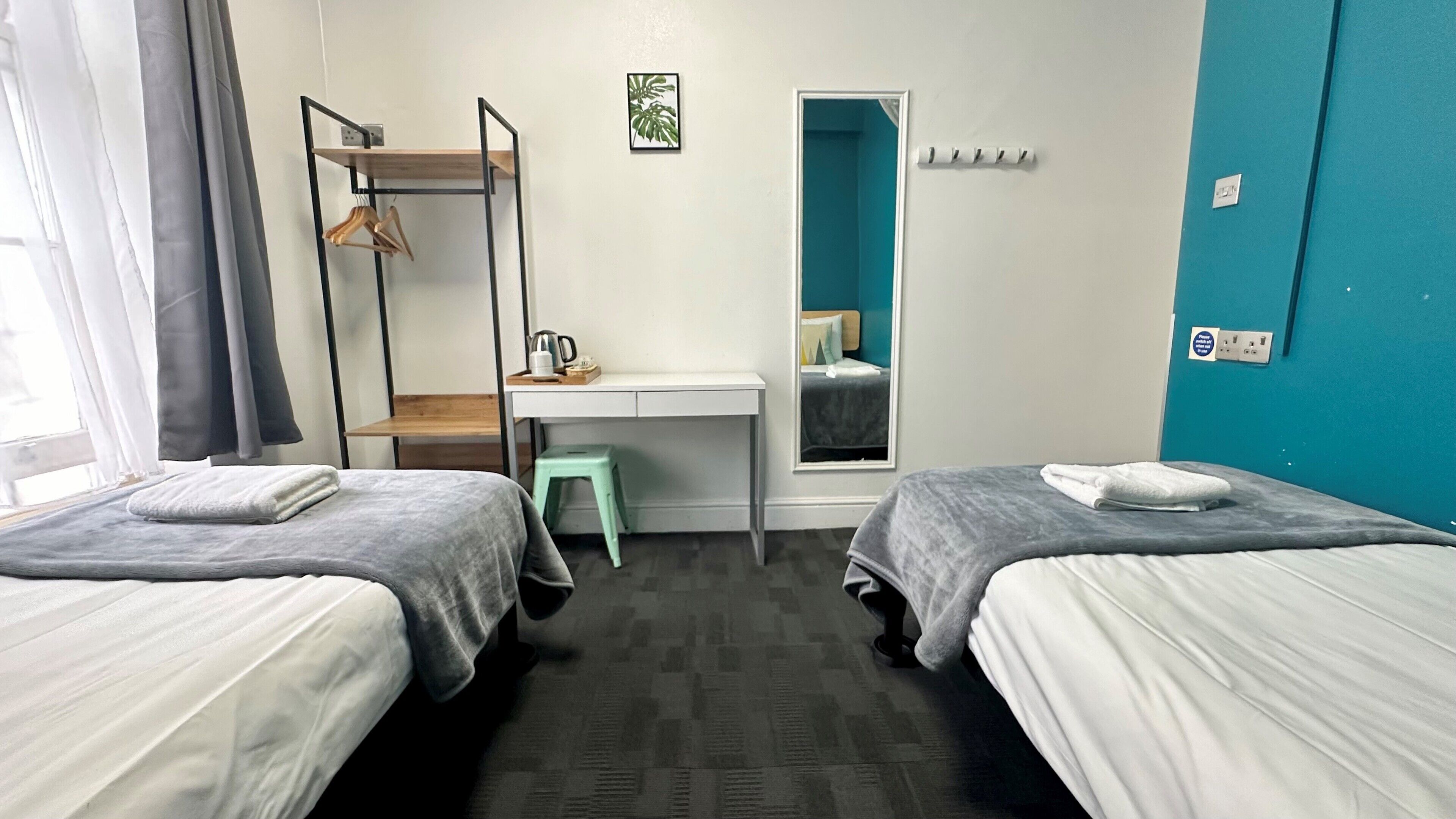 Habitación de hotel con dos camas, un escritorio, una silla, un armario y una ventana.
