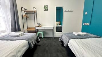 Habitación de hotel con dos camas, un escritorio, una silla, un armario y una ventana.