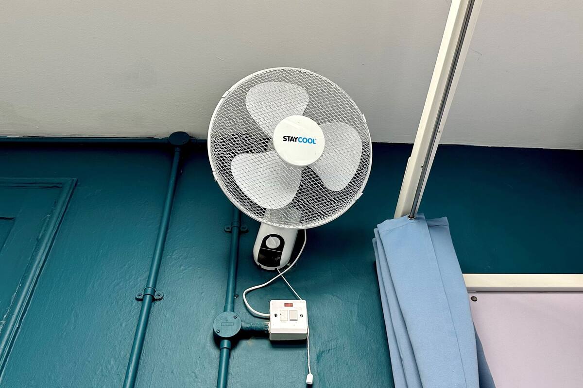 A wall-mounted fan with a control box and power cord.