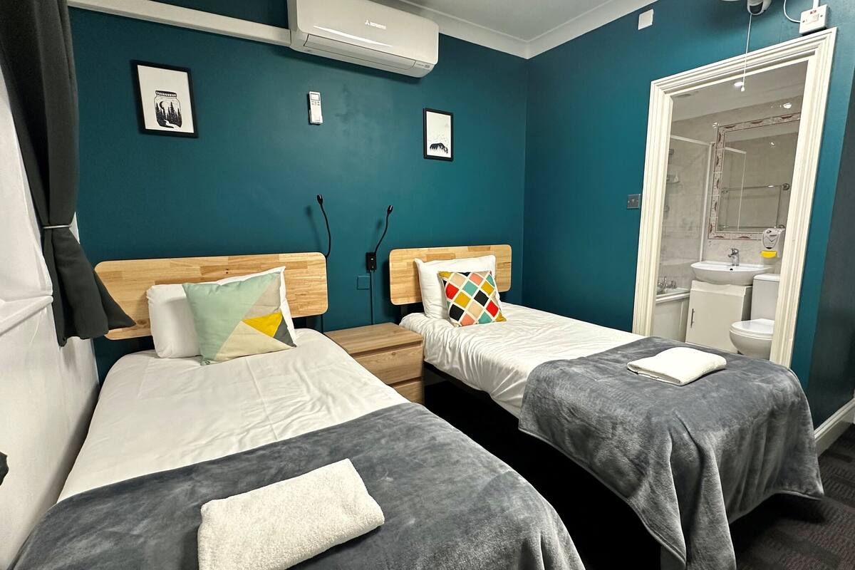 A hotel room with two beds, a bathroom, and a shower.