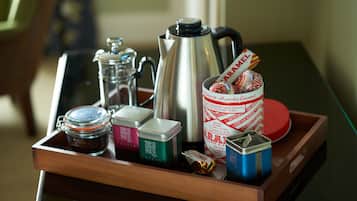 Ein Tablett mit einer Kaffeemaschine, einem Einmachglas, einer Dose Sahne und einer Dose Tee sowie einer Dose Kekse.