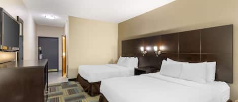 Ein Hotelzimmer mit zwei Betten, einem Schreibtisch, einem Fernseher und einem gemusterten Teppich.