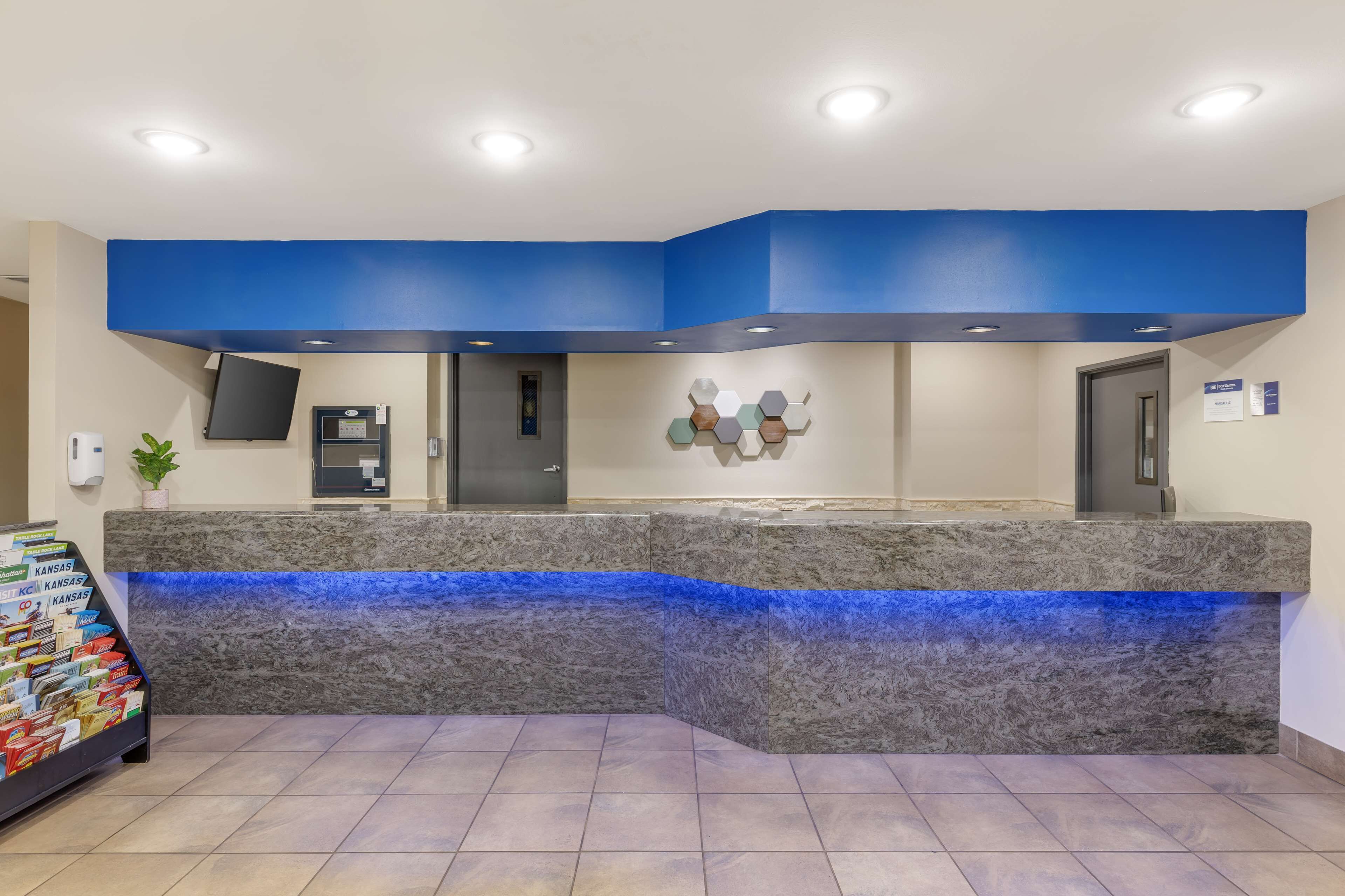 A reception area with a blue accent wall, a marble counter, a flat-screen TV, and a plant.