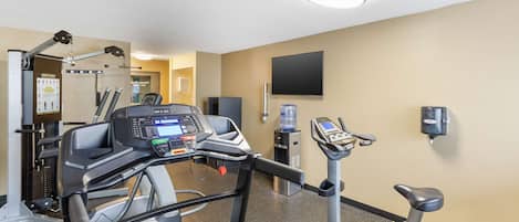 Une salle de sport équipée de tapis de course, de vélos d’appartement et d’appareils de musculation.