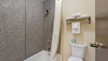 A bathroom with a bathtub, shower, toilet, and towel rack.