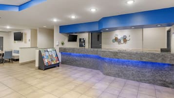 Un'area reception con parete decorata in blu, un bancone in marmo e un chiosco self-service.