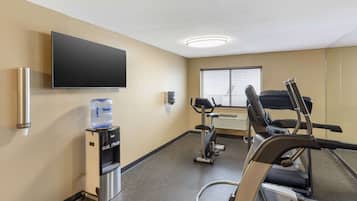 A fitness room with a water dispenser, a television, and exercise equipment.