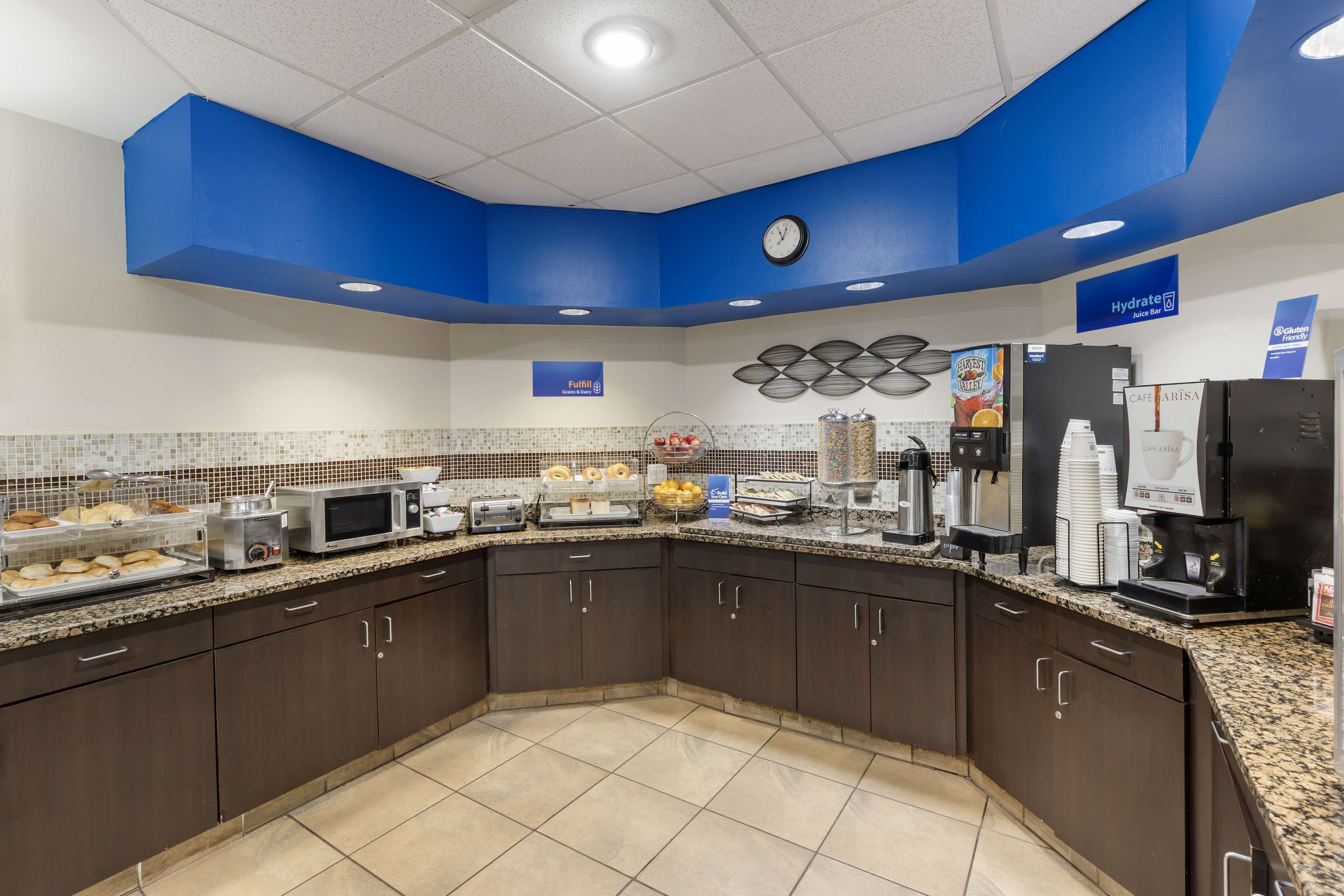 A breakfast bar with a clock, a juice bar, and a coffee station.