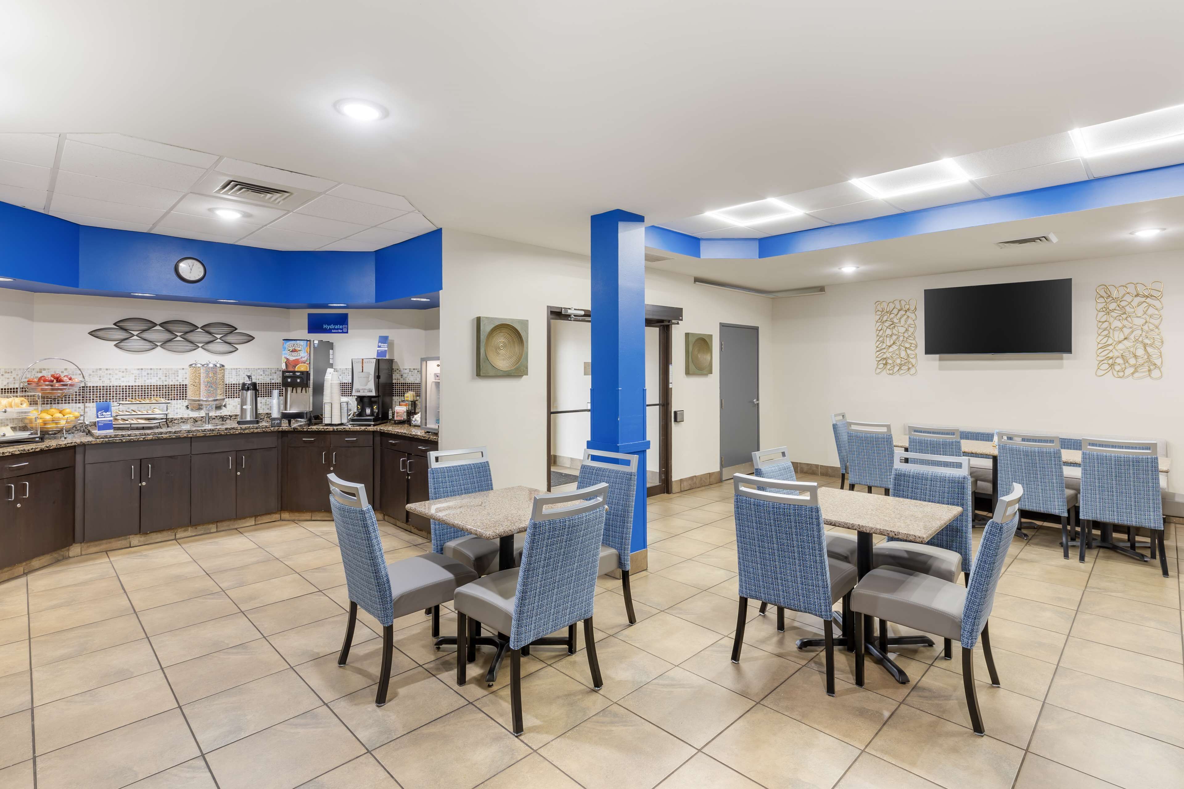 A modern restaurant with blue accents, a kitchen area, and a seating arrangement.