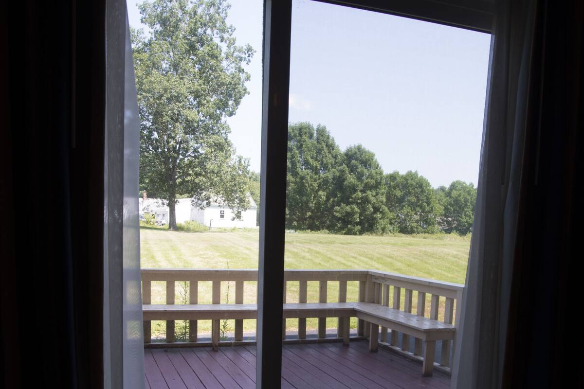 Une pièce dotée d’une grande porte-fenêtre coulissante qui donne sur une terrasse extérieure avec un banc en bois.