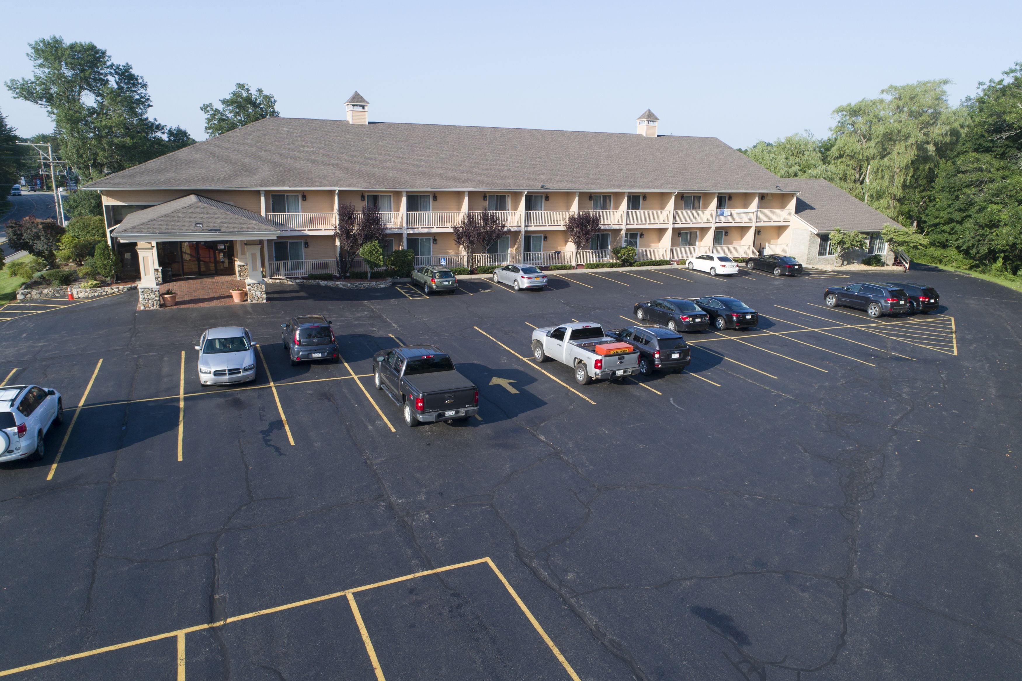 A multi-story motel with a parking lot containing various vehicles.