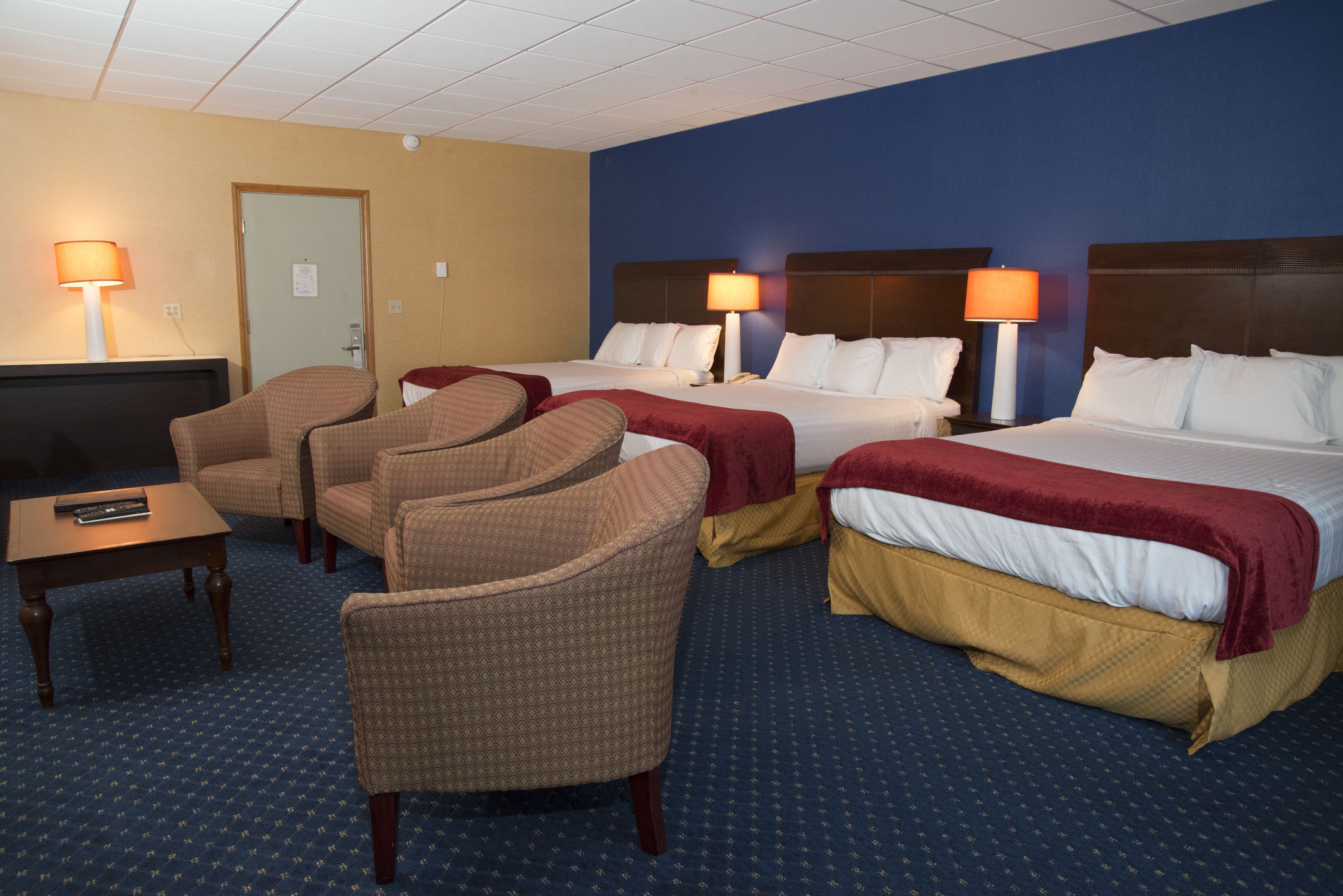 Habitación de hotel con dos camas, televisión y varias zonas de estar.
