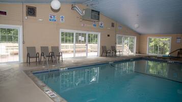 An indoor swimming pool with clear glass doors, a ceiling fan, and a no-pets sign.