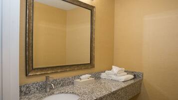 A bathroom with a granite countertop sink, a mirror, and a towel rack.