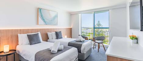 Une chambre d’hôtel avec deux lits, un bureau, une chaise, une télévision et un balcon avec vue.