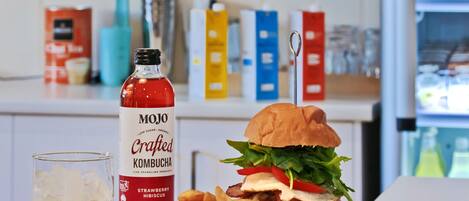 Ein Essen mit einem Burger, Pommes und einer Flasche Kombucha auf einem Tisch.