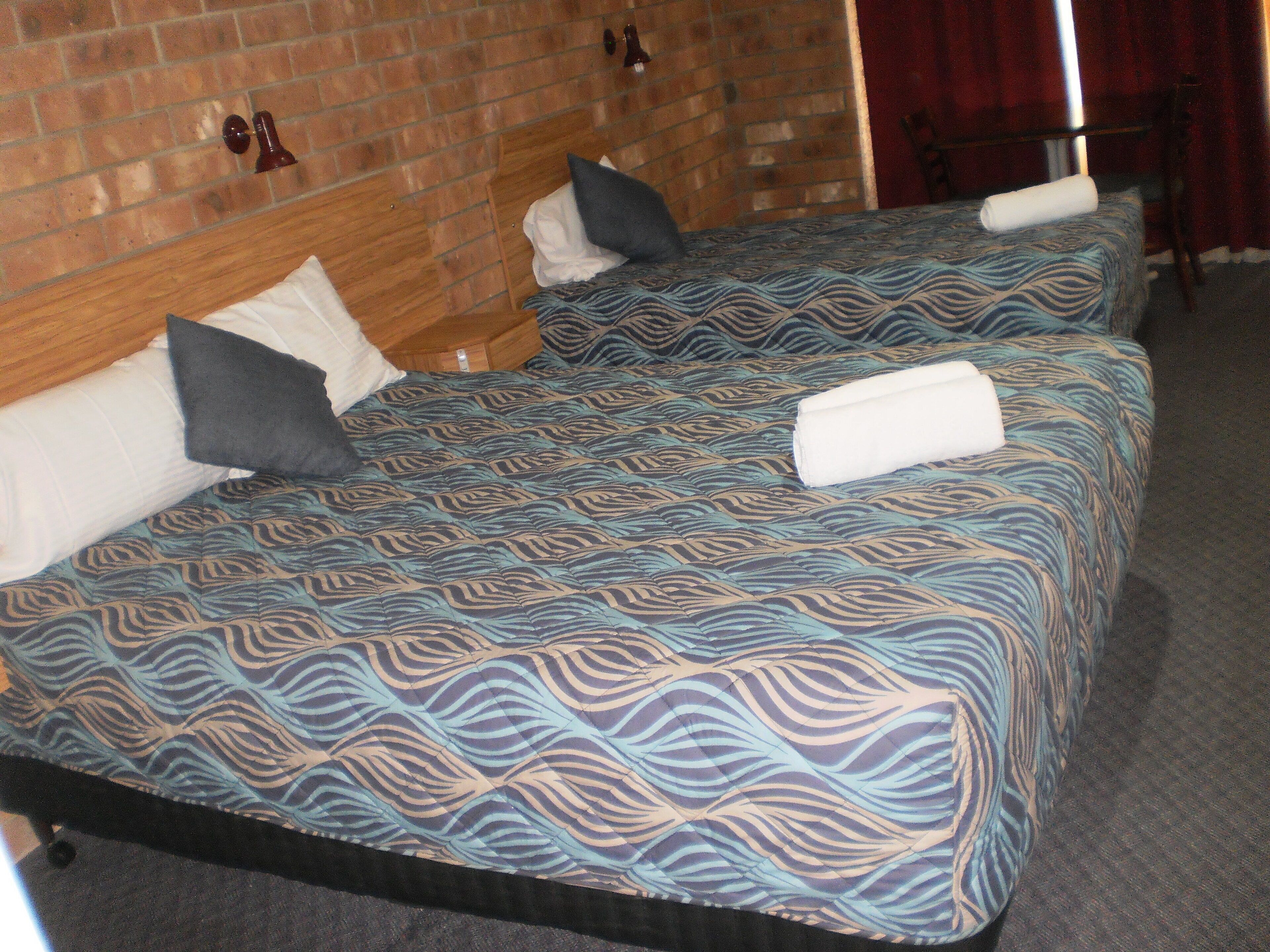 Una habitación de hotel con dos camas, cada una con ropa de cama y almohadas estampadas.