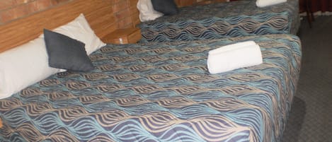 Una habitación de hotel con dos camas, cada una con ropa de cama y almohadas estampadas.