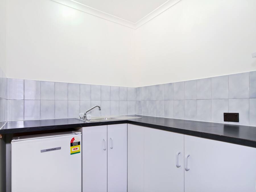 A kitchen with white cabinets, a black countertop, and a stainless steel sink.
