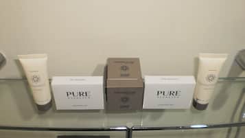 A bathroom shelf with three bottles of shampoo, two boxes of soap, and a shower cap.