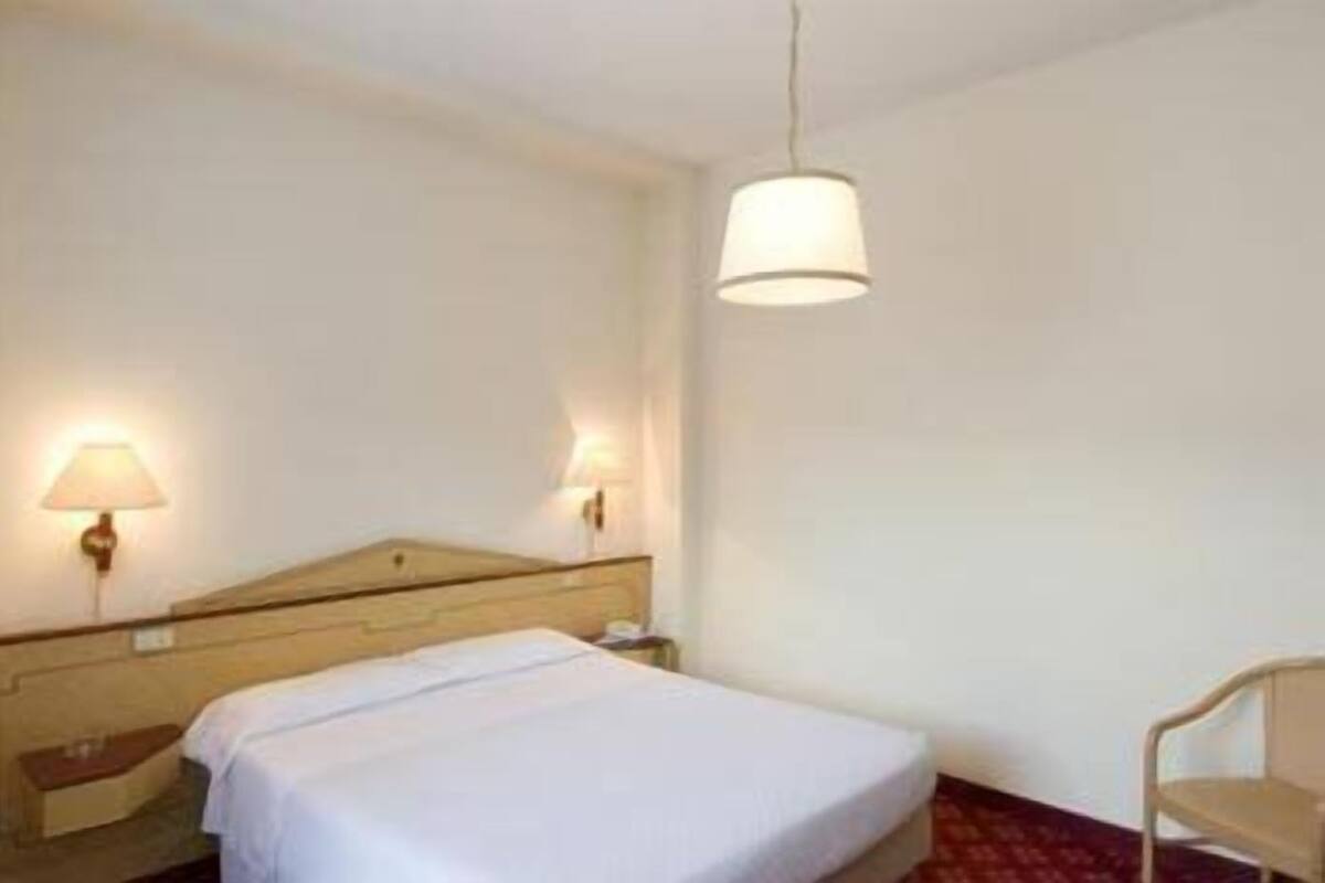 Une chambre d’hôtel avec un lit, des lampes de chevet et un luminaire suspendu.