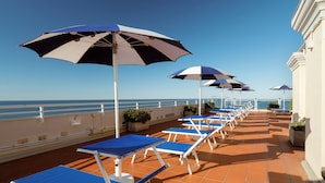 A sun deck with blue lounge chairs and umbrellas, overlooking the sea. - Grand Hotel Astoria (Grado)