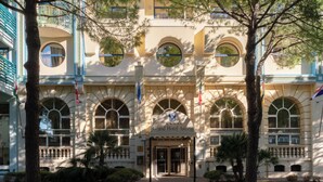A grand hotel entrance with a symmetrical facade, arched windows, and a central entrance. - Grand Hotel Astoria (Grado)