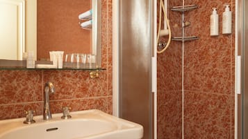 Un baño con lavamanos, espejo y zona de ducha.