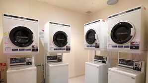 Three stacked laundry machines in a room with a blue mat on the floor.