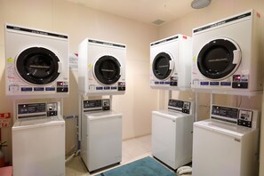 Tres lavadoras apiladas en una habitación con un tapete azul en el suelo.
