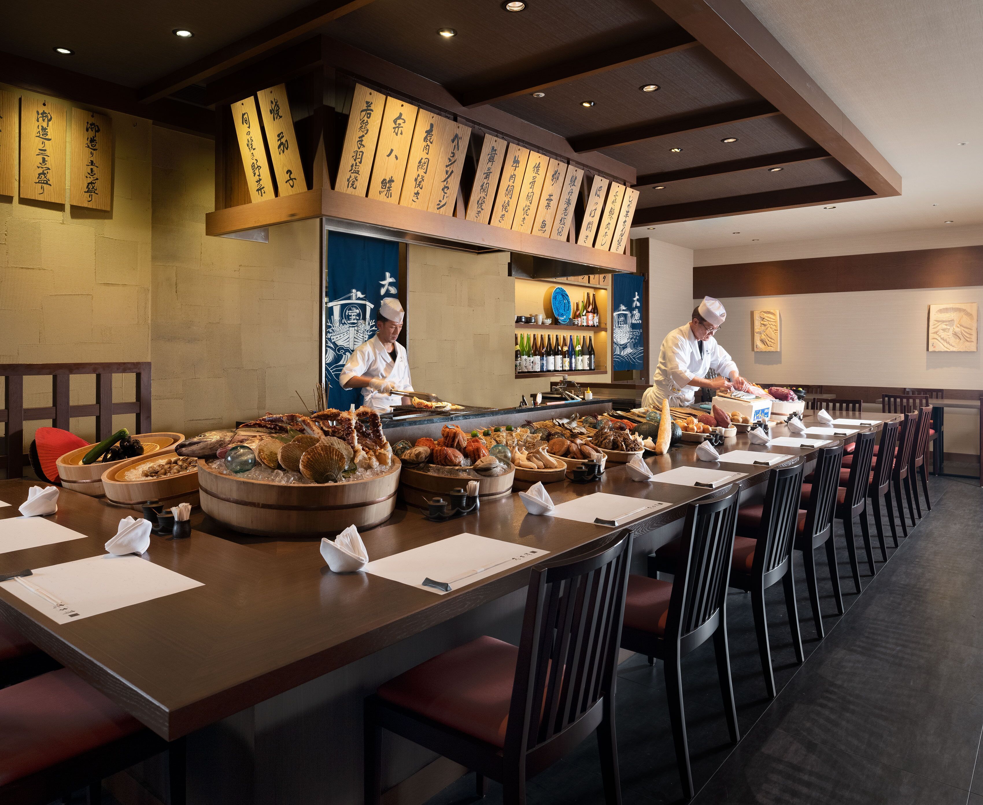 Un restaurant doté d’une longue table à manger, de plusieurs buffets et d’un bar à sushis.