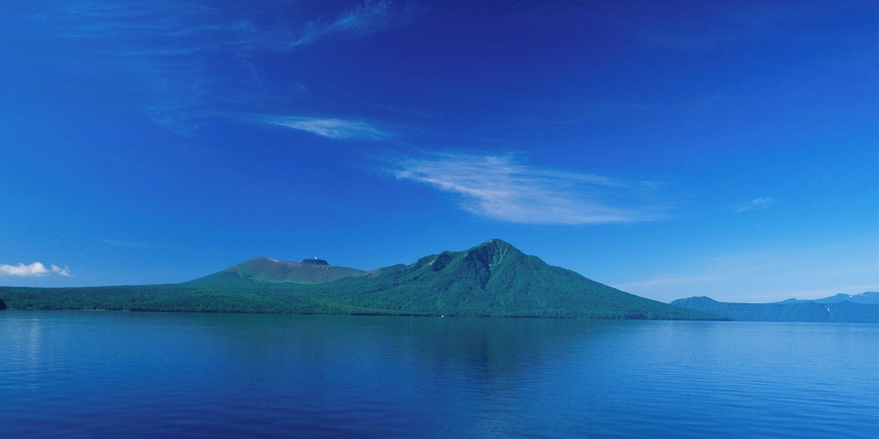 Een berg met een heldere lucht en stilstaand water op de voorgrond.