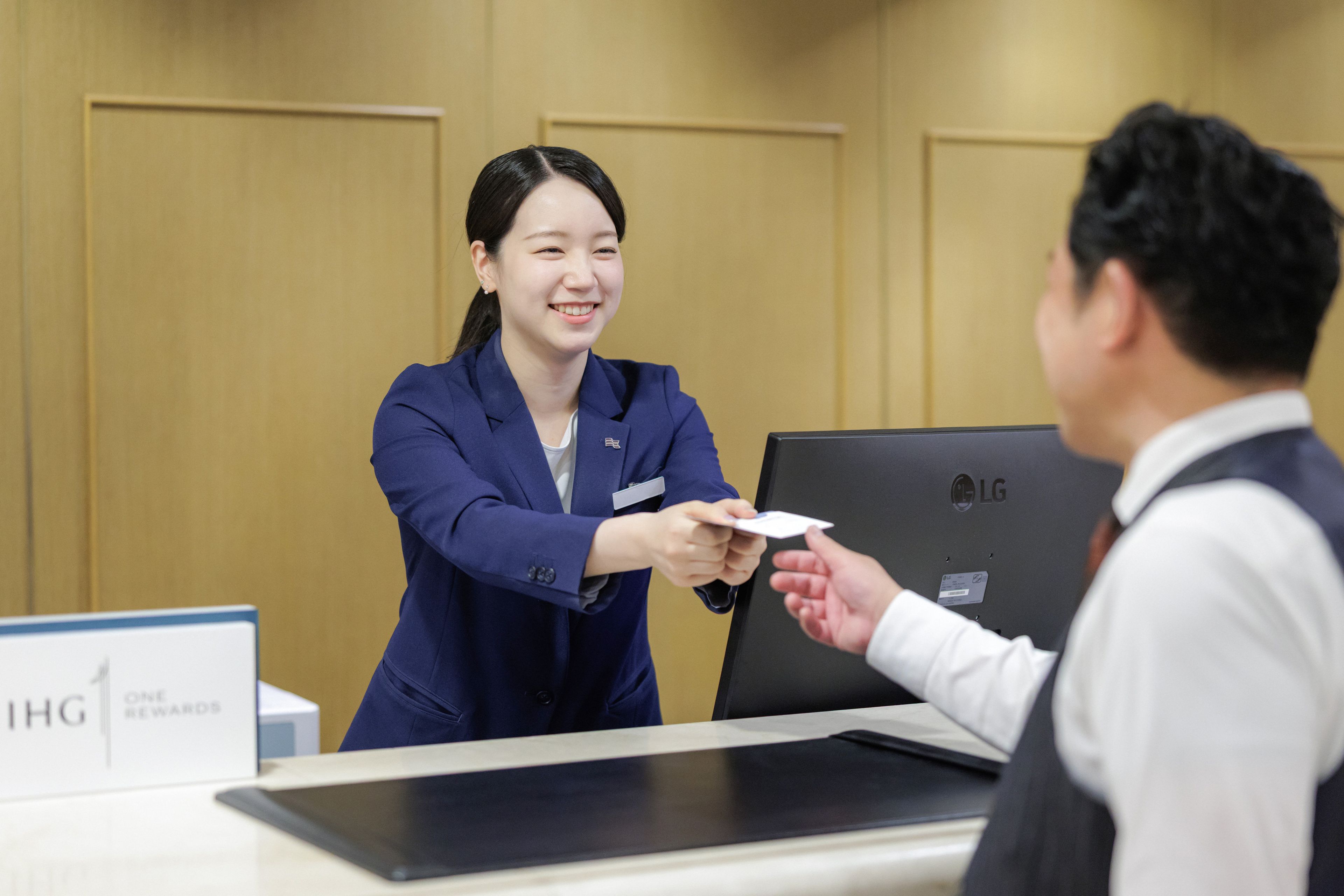 A reception desk with a nameplate, a laptop, and a sign indicating a one-reward policy.