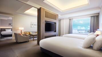 Quarto de hotel moderno com uma cama grande, televisão, área de estar e vista para a cidade.